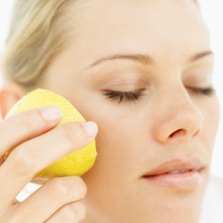 Close-up of a woman rubbing half a lemon to her cheek